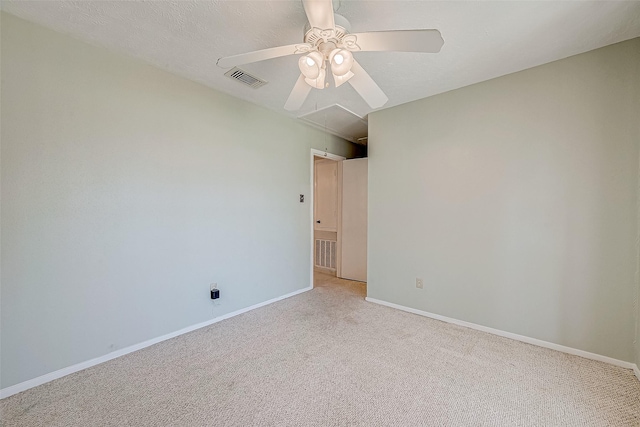 unfurnished room featuring visible vents, light carpet, a ceiling fan, baseboards, and attic access