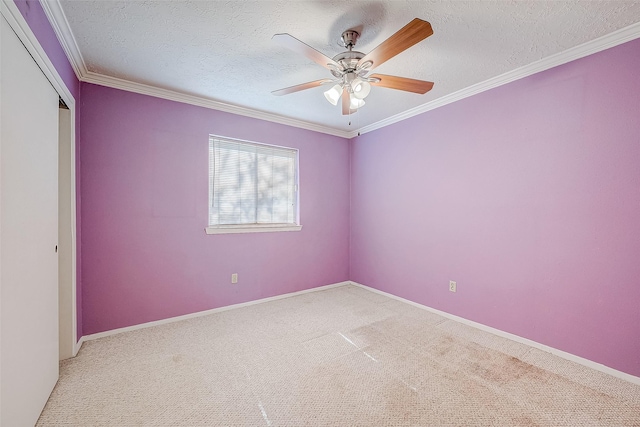 empty room featuring light carpet, ornamental molding, a ceiling fan, a textured ceiling, and baseboards