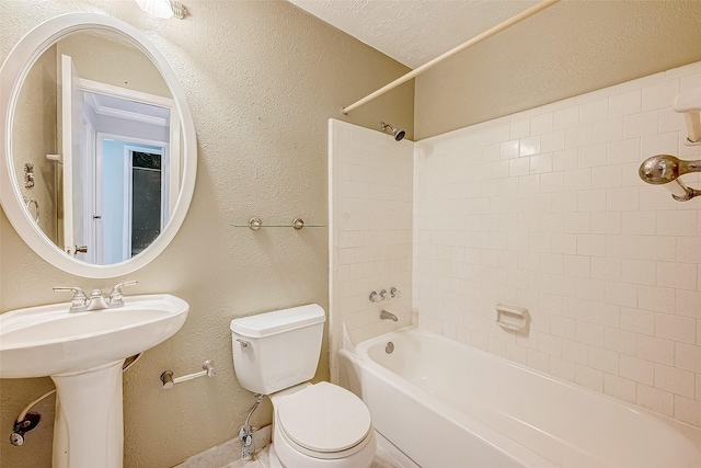 bathroom featuring toilet, a sink, a textured ceiling, tub / shower combination, and a textured wall