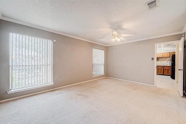 empty room featuring a textured ceiling, light colored carpet, baseboards, and ornamental molding