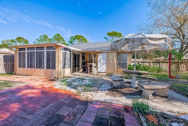 back of property featuring a patio area, fence, and a sunroom