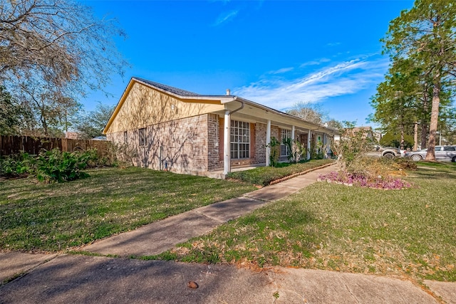 view of property exterior with a yard, brick siding, and fence