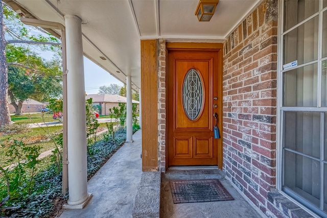 property entrance with brick siding and a porch