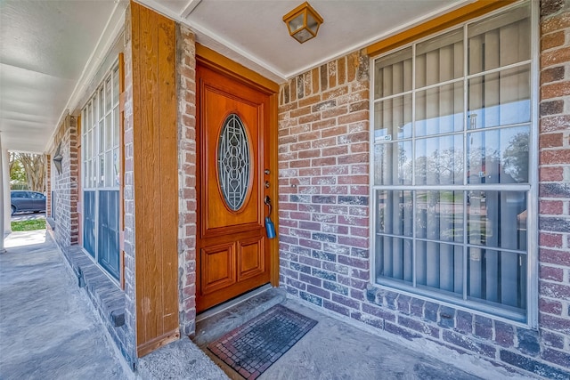 entrance to property featuring brick siding and covered porch