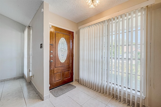 entrance foyer featuring a wealth of natural light, tile patterned floors, a textured ceiling, and baseboards