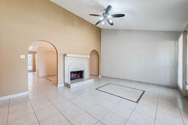 unfurnished living room featuring light tile patterned flooring, a tiled fireplace, a textured ceiling, and arched walkways