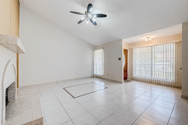 unfurnished living room with light tile patterned floors, a ceiling fan, a fireplace, vaulted ceiling, and a textured ceiling