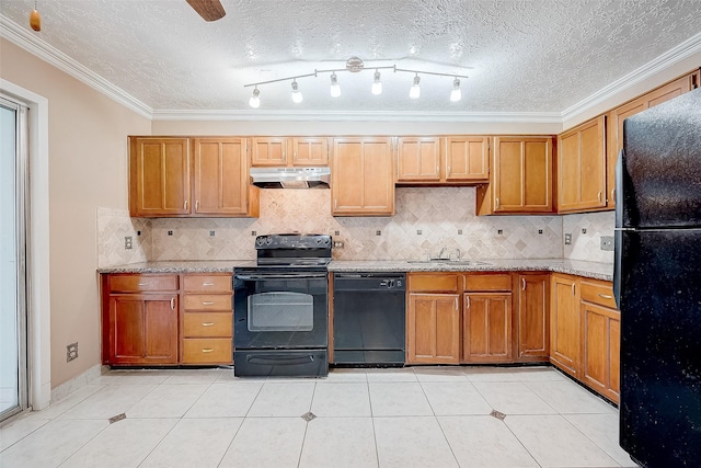 kitchen with under cabinet range hood, ornamental molding, light tile patterned floors, black appliances, and a sink