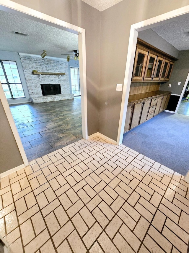 kitchen featuring a healthy amount of sunlight, ceiling fan, a fireplace, and a textured ceiling