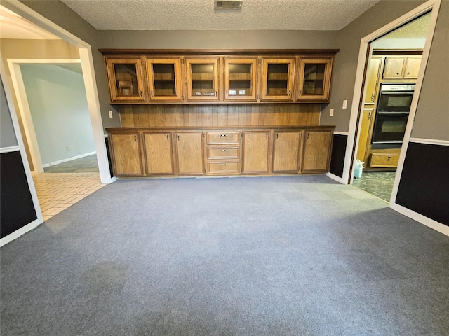 interior space featuring light carpet, stainless steel double oven, and a textured ceiling