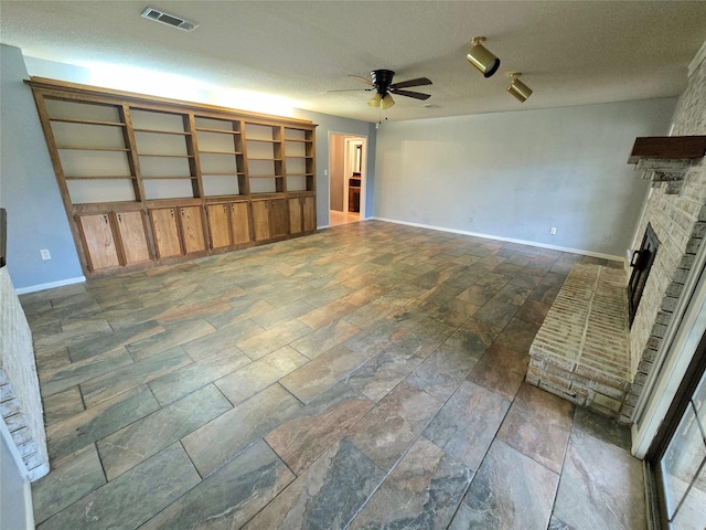 unfurnished living room featuring ceiling fan, a textured ceiling, and a fireplace