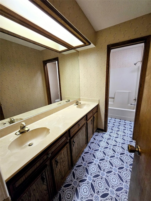 bathroom with tile patterned flooring, vanity, and a textured ceiling