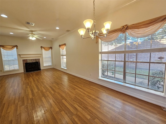 unfurnished living room featuring a tile fireplace, crown molding, ceiling fan with notable chandelier, and hardwood / wood-style flooring