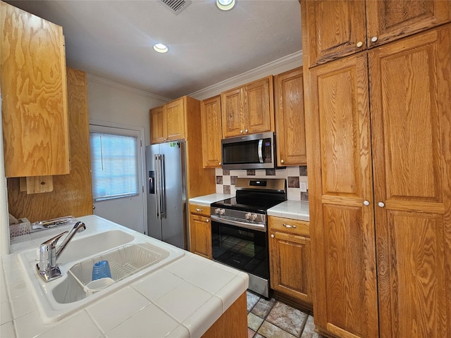 kitchen featuring stainless steel appliances, tile counters, crown molding, and sink