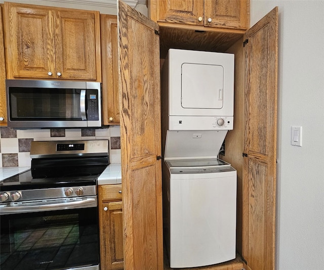 kitchen featuring stacked washer / drying machine, decorative backsplash, and stainless steel appliances