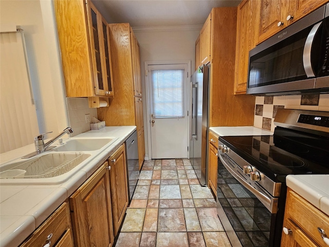 kitchen with tile countertops, crown molding, sink, appliances with stainless steel finishes, and tasteful backsplash