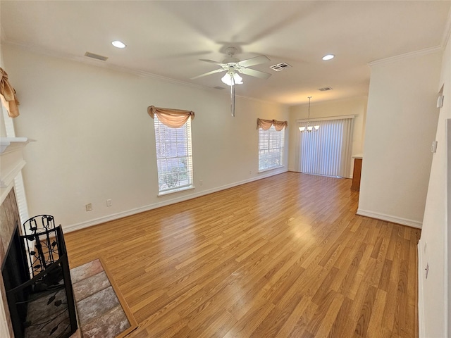 unfurnished living room featuring ceiling fan with notable chandelier, light hardwood / wood-style floors, and crown molding