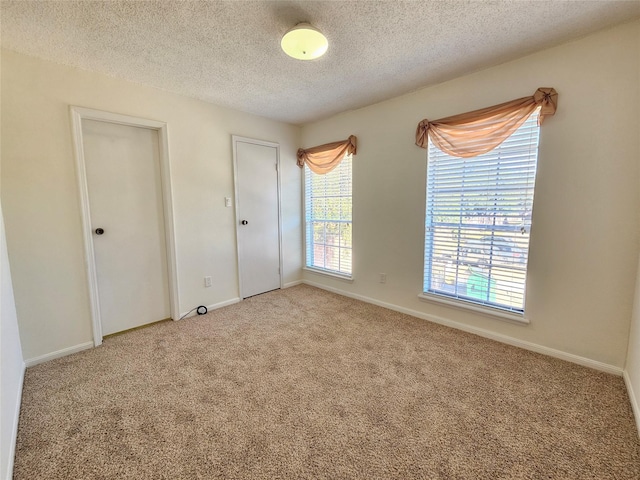 unfurnished bedroom featuring light colored carpet and a textured ceiling