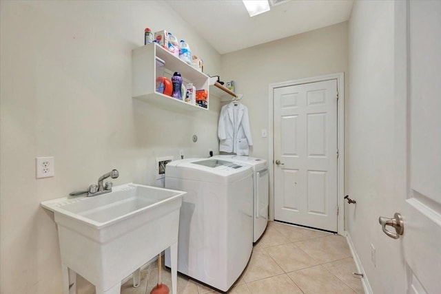 clothes washing area with light tile patterned flooring, sink, and washing machine and clothes dryer