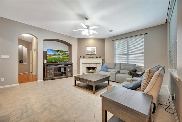 tiled living room featuring ceiling fan and a fireplace