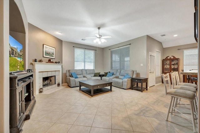 tiled living room featuring ceiling fan and a tiled fireplace