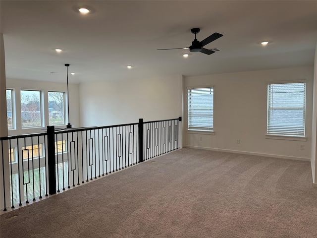 unfurnished room with a wealth of natural light, ceiling fan, and light carpet