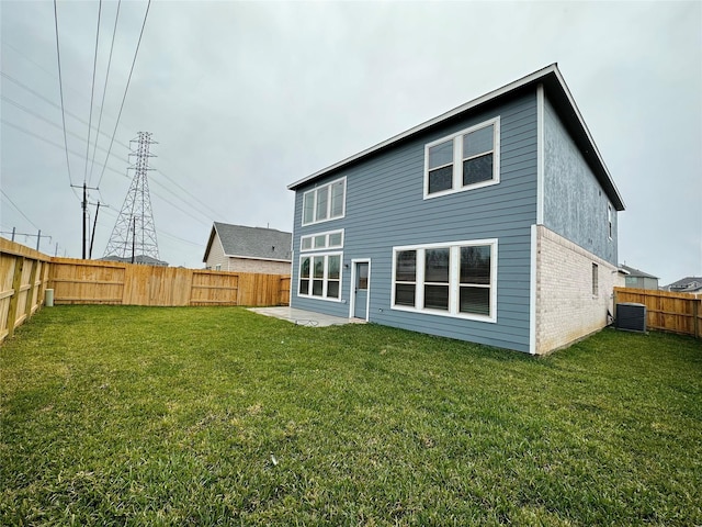 rear view of house with central AC and a lawn