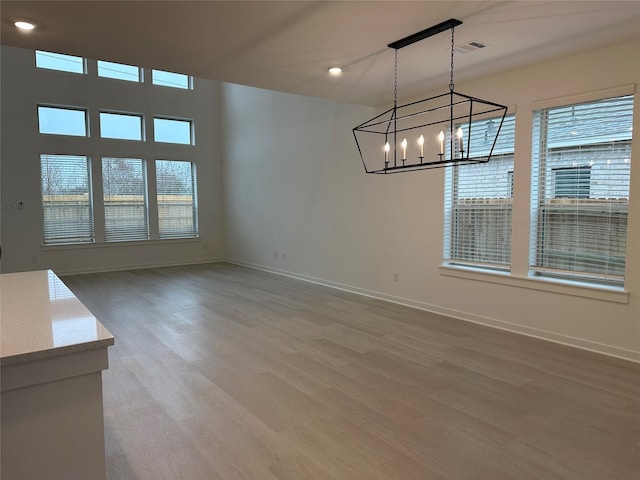 unfurnished dining area with hardwood / wood-style floors, plenty of natural light, and a notable chandelier