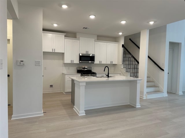 kitchen featuring kitchen peninsula, light wood-type flooring, white cabinetry, and stainless steel appliances