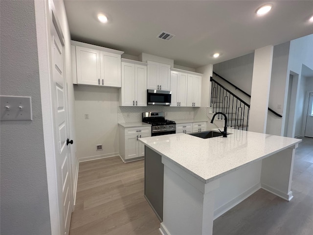 kitchen with white cabinetry, sink, appliances with stainless steel finishes, and an island with sink