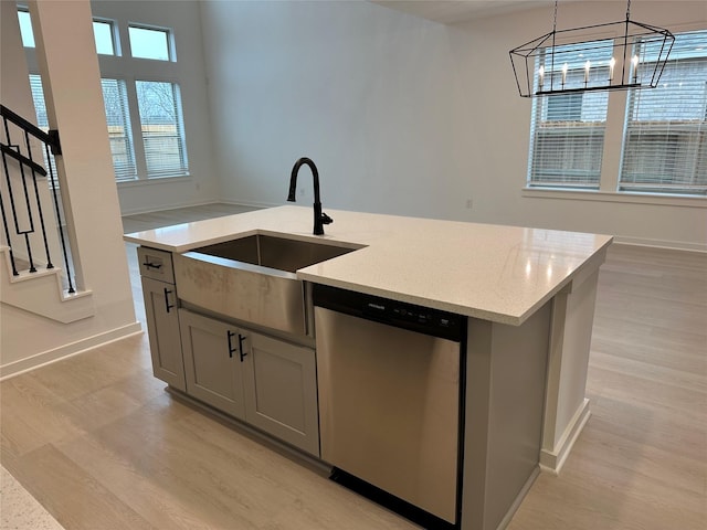 kitchen featuring gray cabinetry, dishwasher, sink, hanging light fixtures, and a center island with sink