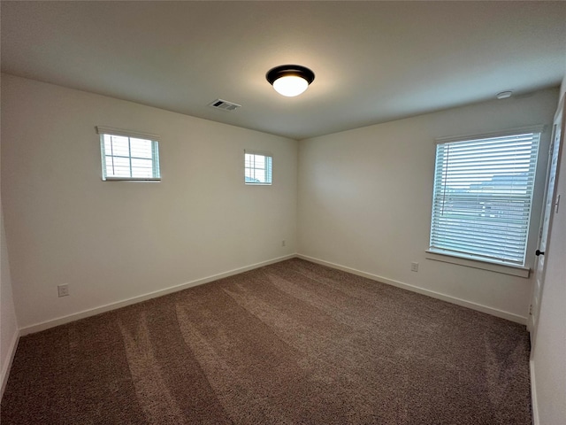 unfurnished room featuring a wealth of natural light and dark carpet