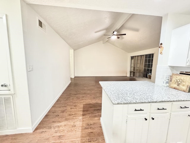 kitchen featuring white cabinetry, ceiling fan, vaulted ceiling with beams, light stone counters, and light hardwood / wood-style floors