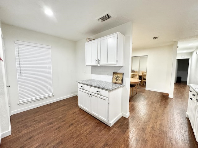 kitchen with decorative backsplash, dark hardwood / wood-style flooring, white cabinets, and light stone counters