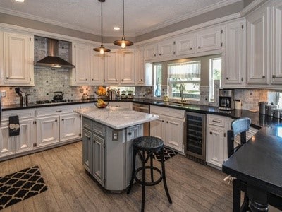 kitchen featuring a center island, sink, beverage cooler, wall chimney range hood, and white cabinets