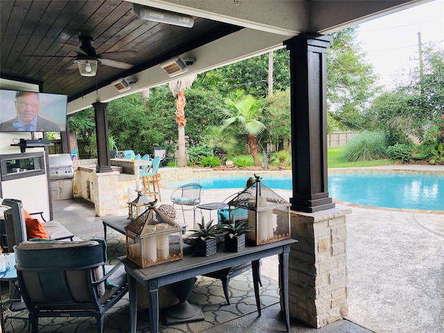 view of patio featuring a bar, a fenced in pool, ceiling fan, and exterior kitchen