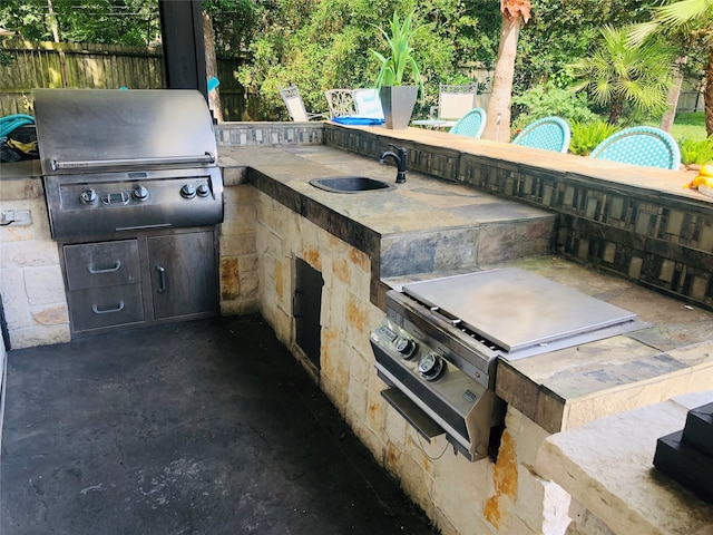 view of patio with sink, an outdoor kitchen, and a grill