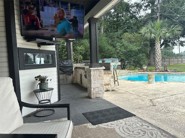 view of patio / terrace featuring an outdoor kitchen, a fenced in pool, and an outdoor bar