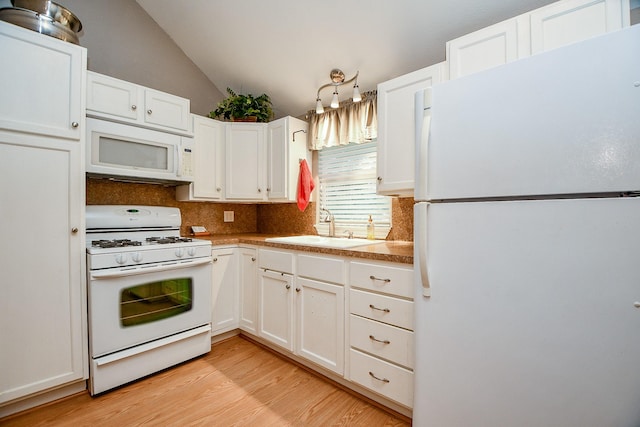 kitchen with sink, white cabinetry, vaulted ceiling, light wood-type flooring, and white appliances