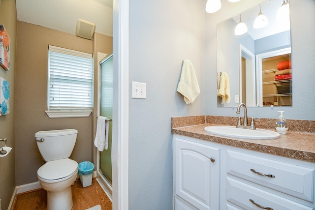 bathroom featuring a shower with door, vanity, hardwood / wood-style flooring, and toilet