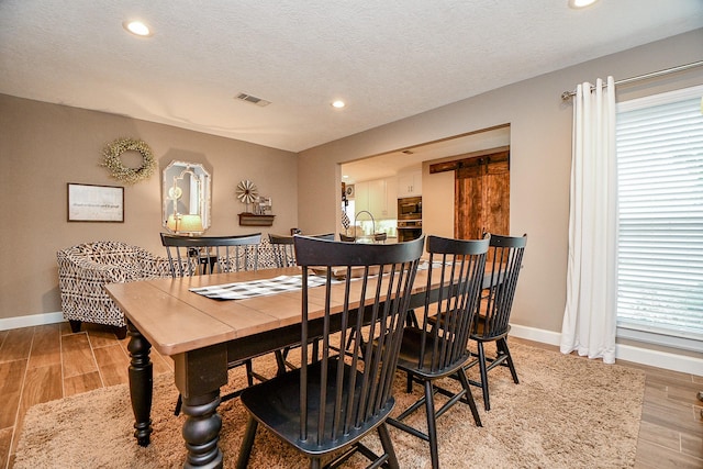 dining space featuring a textured ceiling and light wood-type flooring