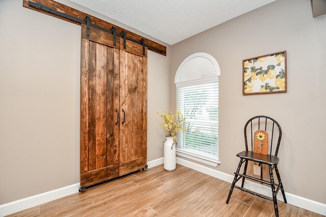 sitting room with light hardwood / wood-style floors, a barn door, and a textured ceiling