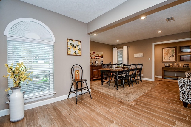 dining area with light hardwood / wood-style floors and a textured ceiling