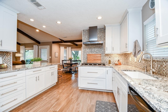 kitchen with sink, light hardwood / wood-style flooring, appliances with stainless steel finishes, white cabinetry, and wall chimney exhaust hood