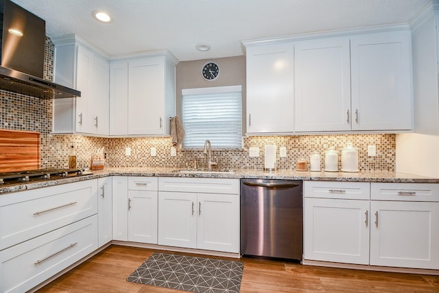 kitchen featuring sink, white cabinetry, stainless steel appliances, light stone counters, and wall chimney exhaust hood