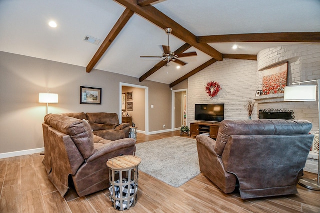 living room with ceiling fan, light hardwood / wood-style floors, a brick fireplace, and vaulted ceiling with beams