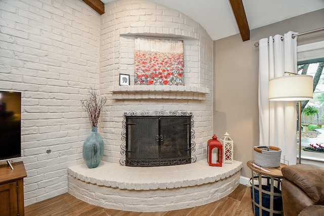 living room with hardwood / wood-style flooring, a fireplace, and vaulted ceiling with beams