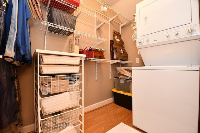 spacious closet with wood-type flooring and stacked washing maching and dryer