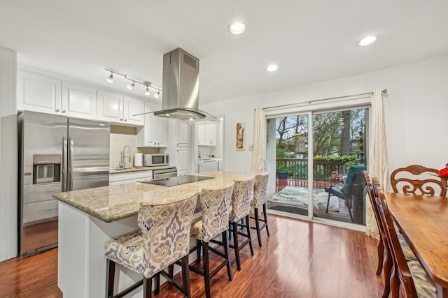 kitchen featuring island exhaust hood, black electric cooktop, independent washer and dryer, stainless steel fridge with ice dispenser, and white cabinetry