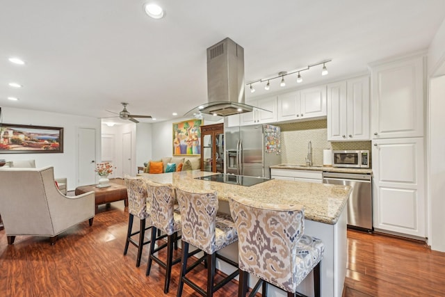 kitchen featuring white cabinets, light stone countertops, tasteful backsplash, island range hood, and stainless steel appliances